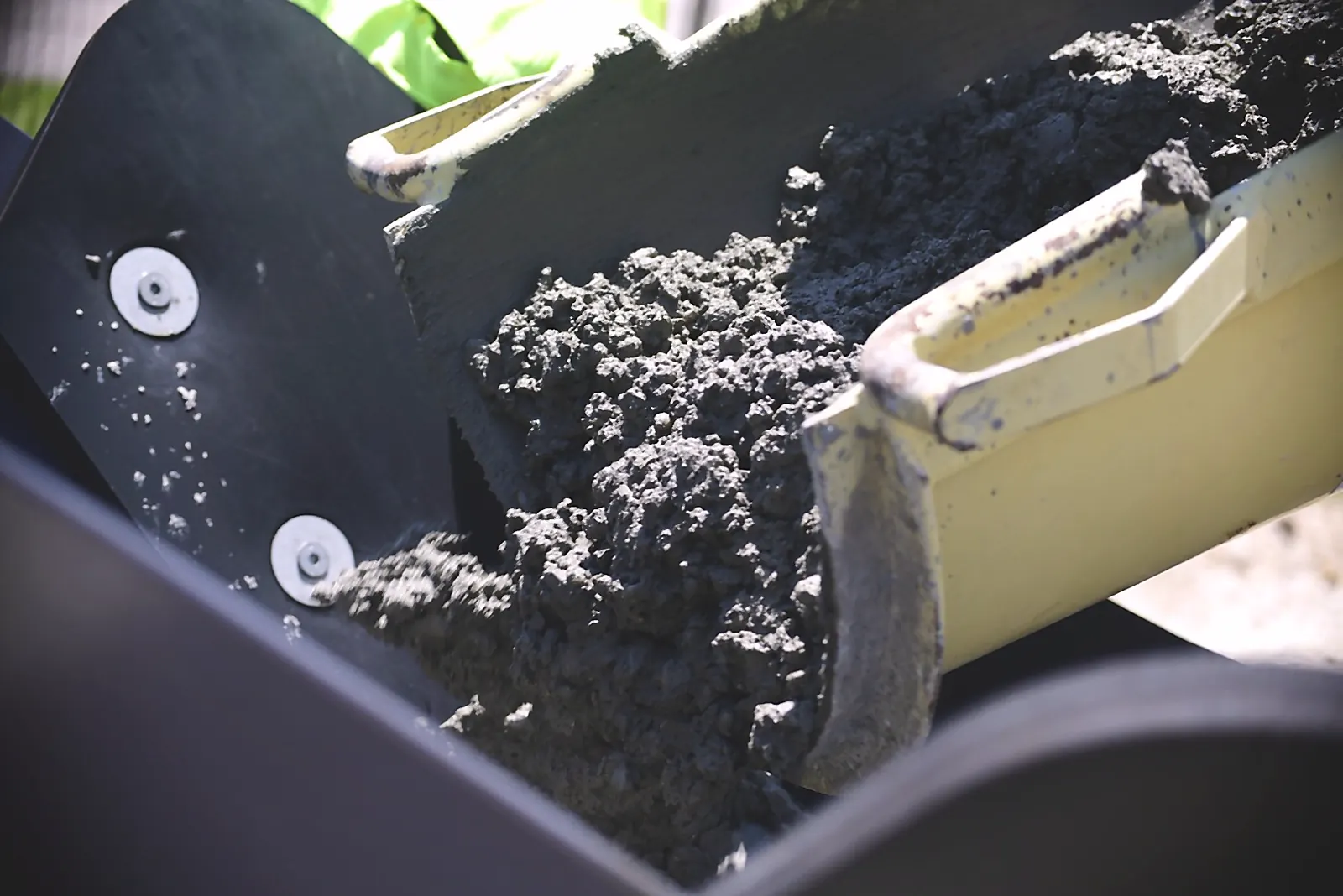 Fresh concrete flowing from the Wirtgen slip-form curb machine screed